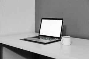 A clean and modern workspace featuring a laptop and white mug on a desk.